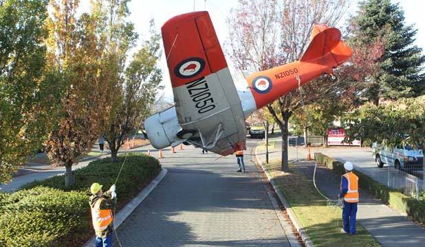 “GUARDIAN OF WIGRAM”: The RNZAF North American Harvard which sits on a plinth at the Air Force Museum is lifted off for a spruce-up. — DON SCOTT/The Press.