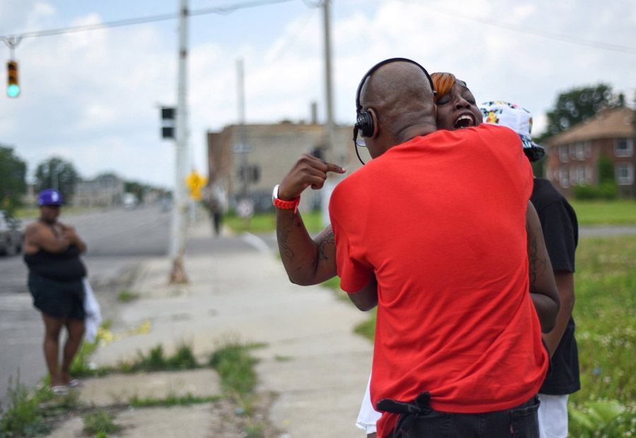 A woman is hugged by Sanford D. Miles near the scene of a block party where three men exchanged gunfire in Detroit on June 21st, 2015. — Photo: Tanya Moutzalias/Associated Press.