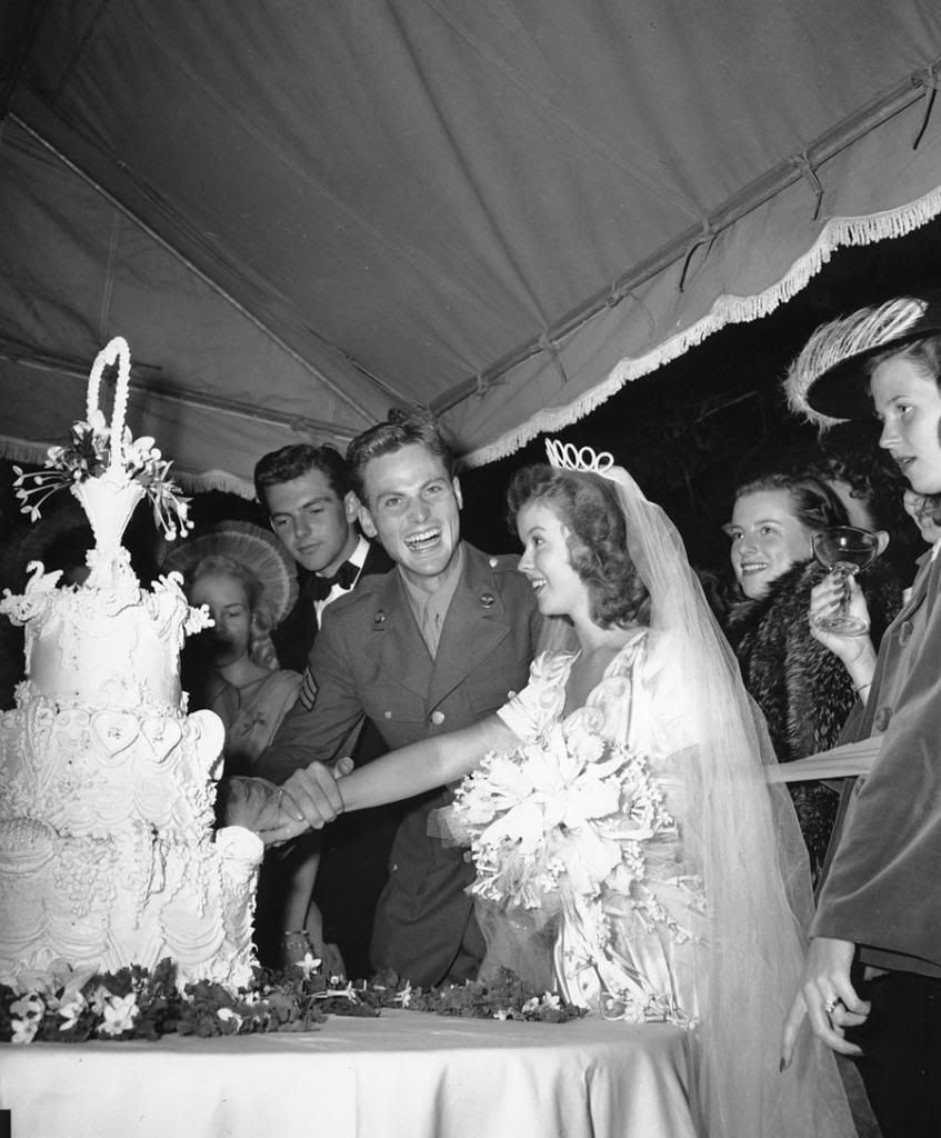 Newlyweds Shirley Temple and Sergeant John Agar Jr. cut their wedding cake beneath a tent on the lawn of the Temple estate on September 19th, 1945. — Photo: Associated Press.