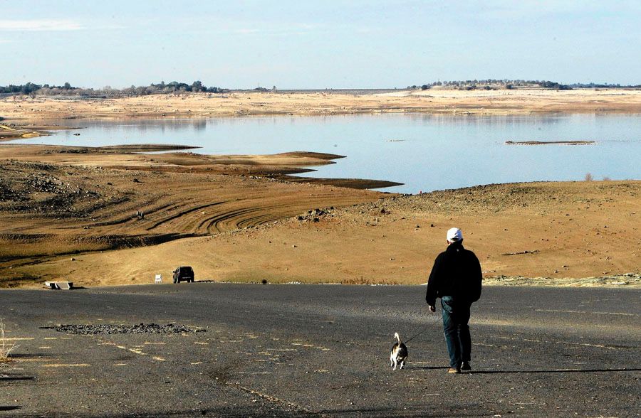 A visitor to Folsom Lake in California's Central Valley walks his dog down a boat ramp that is now several hundred yards from the water's edge. At a mere 17% capacity, the lake has become a visual symbol of California's water crisis. — Photo: Rich Pedroncelli/Associated Press.