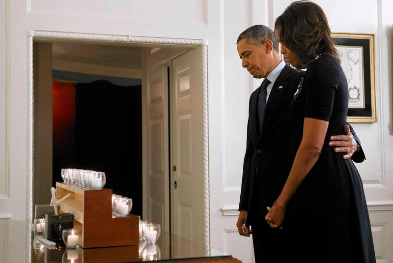 President Obama and First Lady Michelle Obama take a moment of silence for the 26 killed a year ago Saturday at Sandy Hook Elementary School. Gun safety legislation fell short in Congress after the massacre. — Photo: Saul Loeb/AFP/Getty Images.