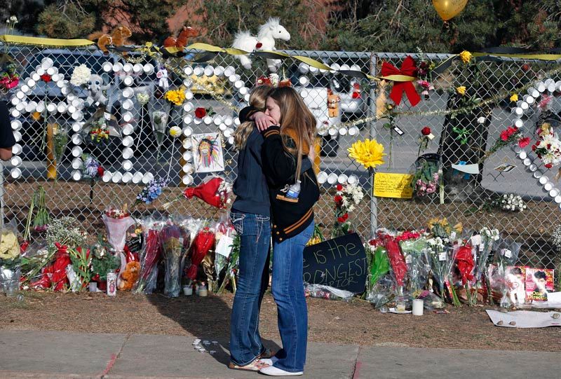 Arapahoe High School students hug at a tribute site honoring senior Claire Davis, who was hospitalized after being shot in the head by a fellow student on December 13th. Davis died Saturday afternoon. — Photo: Brennan Linsley/Associated Press.