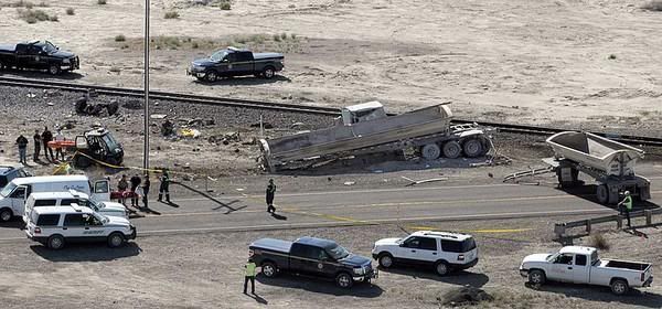 Emergency crews investigate the site of the collision. Wreckage of the semi-truck is strewn near the tracks. — Photo: Marilyn Newton/Associated Press/June 24, 2011.