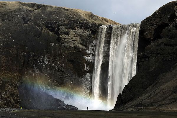 DIRTY WATER: A woman stands near a waterfall that has been dirtied by ash that has accumulated from the ash plume of an erupting volcano near Eyjafjallajokull.  REUTERS.