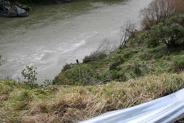 A man stands at the edge of the Manawatu River where a car crashed this morning. — FAITH SUTHERLAND/Manawatu Standard.