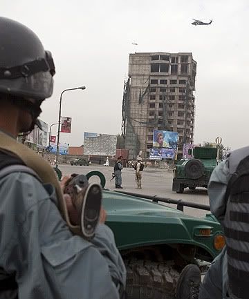 IN THE HEART OF THE CITY: Afghan police watch as a Nato helicopter flies overhead during a battle with Taleban insurgents who took over a building near the US embassy in Kabul.  Photo: REUTERS.