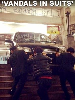 BAD DRIVING: The men try in vain to move their vehicle after getting stuck on an arcade stairs.