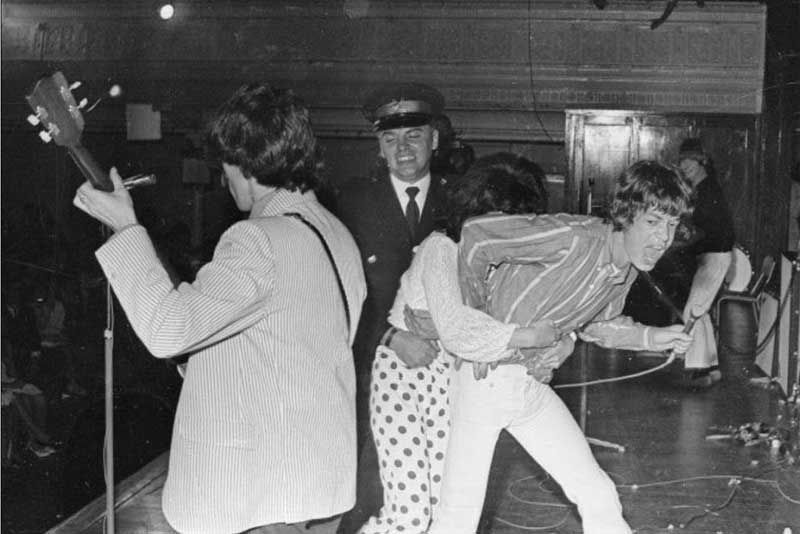 An adoring fan rushes Mick Jagger during a Rolling Stones performance at the Town Hall in 1966.