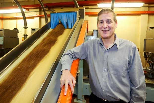 Factory manager Chris Syrigos poses next to a conveyer belt carrying tobacco.  Photo: Hagen Hopkins.