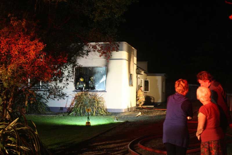 CONCERNED: Residents watch as firefighters work on the house in Masterton.  LYNDA FERINGA/Wairarapa Times-Age.