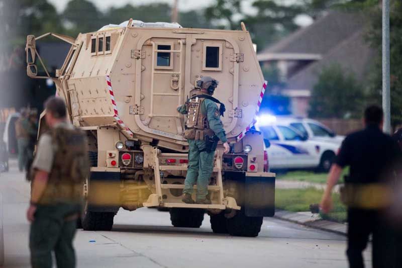 A law enforcement officer rides on the back of an armored vehicle to a standoff with a shooting suspect on Wednesday, July 9th, 2014, in Spring. Seven people were shot, with six confirmed dead. — Photo: Brett Coomer/Houston Chronicle.