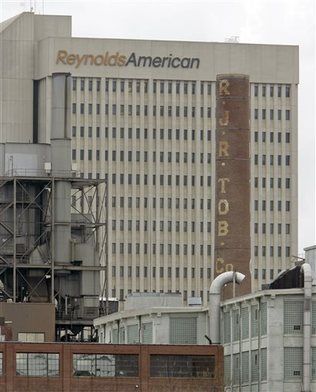 In this February 6th, 2008 photograph, a smokestack of an old R.J. Reynolds Tobacco plant frames the Reynolds American building in Winston-Salem, North Carolina. A Florida jury has slammed R.J. Reynolds Tobacco Company with $23.6 billion in punitive damages in a lawsuit filed by Cynthia Robinson, the widow of a longtime smoker who died of lung cancer in 1996. The damages the jury awarded to Robinson on Friday, July 18th, 2014, after a four-week trial come in addition to $16.8 million in compensatory damages. — Photo: Chuck Burton/Associated Press.