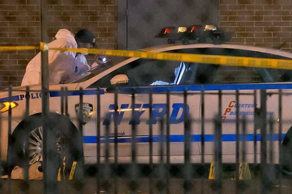 An investigator at the scene where two police officers were fatally shot in Brooklyn on Saturday. — Photo: John Minchillo/Associated Press.