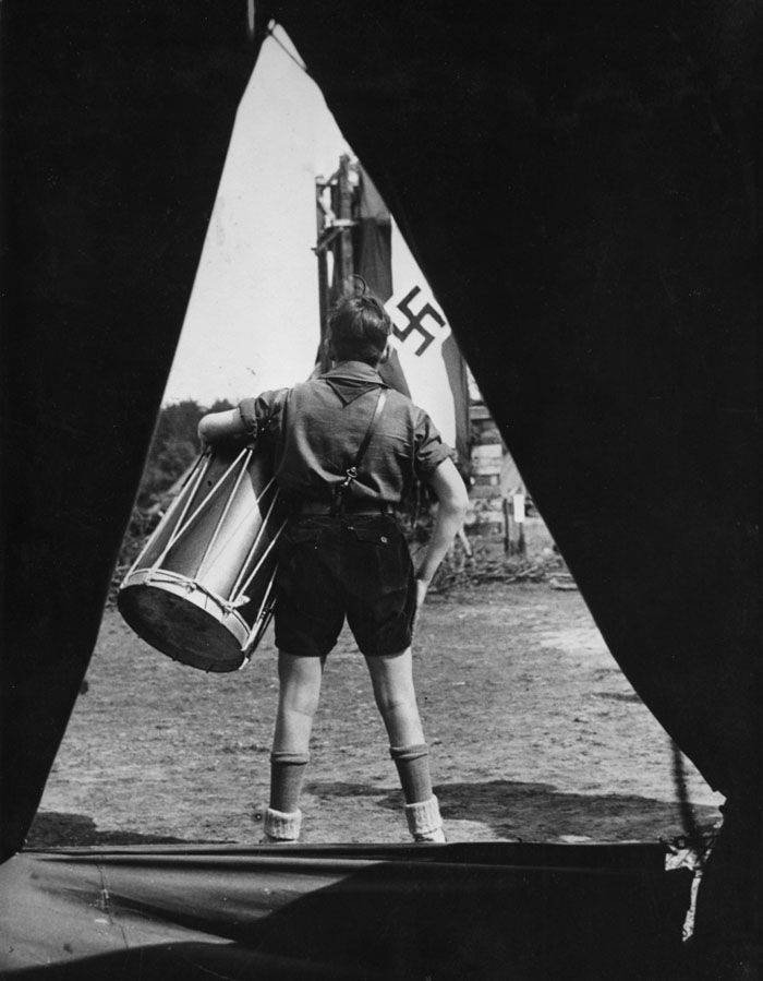 In this undated file photo from the 1930s a member of the Hitlerjugend — HJ (Hitler Youth) wearing his uniform holds a big drum as he stands in front of a tent in a camp looking at a flag of the National Socialists with a swastika on it. — Photo: Associated Press.