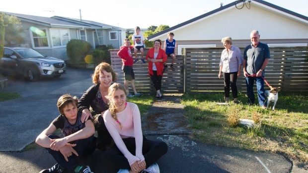 These Paparangi neighbours swap garden goodies, babysit pets and children and were able to navigate conflict by already having a good neighbourly relationship. From left: Alex Masterton, 14, Trish Knight, Grace Masterton, 17, James Martin-Bond, Rowan, 6, Karen and Calum, 9 with Margaret and Peter Penhall and Pipi the foxy.  Photo: Ross Giblin/Fairfax NZ.