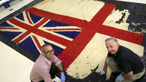 South Canterbury museum social history curator Chris Rapley and naval researcher Fred Wilson CBE unfurl a silk ensign which flew from the HMS New Zealand at the Battle of Jutland in 1916.  Photograph: John Bisset/Fairfax NZ.