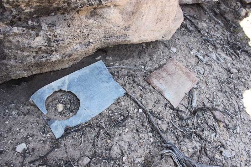 Two pieces of metal, one with a cutout for a stovepipe, lie on the ground near the cave entrance, but no other artifacts have been found other than the remains of a brush corral close to the canyon’s bottom. — Photo: Courtesy of Andrew Guilliford.