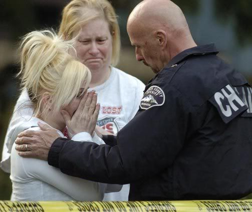 A relative of the deceased children is comforted by a Pierce County Sheriff's deputy in Graham, Wash., Saturday. Washington state investigators say five children between 7 and 16 years old have been found dead in a Graham area home and they may have been killed by their father. JOE BARRENTINE/Associated Press.