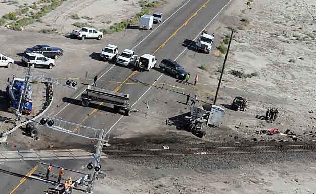 Emergency workers investigate at the site of a collision between an Amtrak westbound train and a truck on U.S. 95 about 4 miles south of Interstate 80 on Friday, 70 miles east of Reno, Nevada. — Photo: Marilyn Newton/Associated Press.