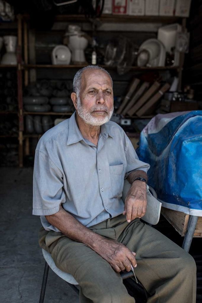 A man sits in front of his shop, which opened right after the conflict.