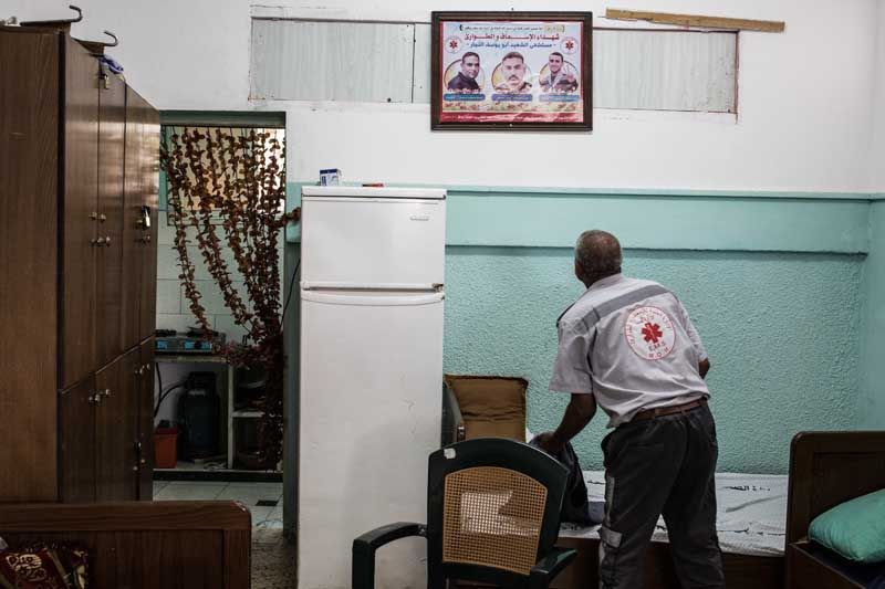Ambulance driver Nawal Abu Amra looks at a picture of the workers who died during the shelling.