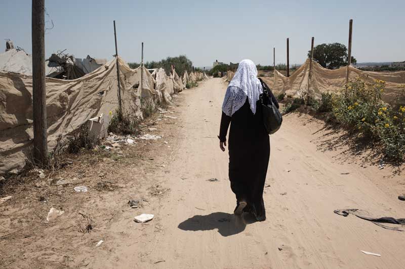 Oum el-Abadia walks along the street where her house once stood.Today, she lives with her 10 children in a tent.