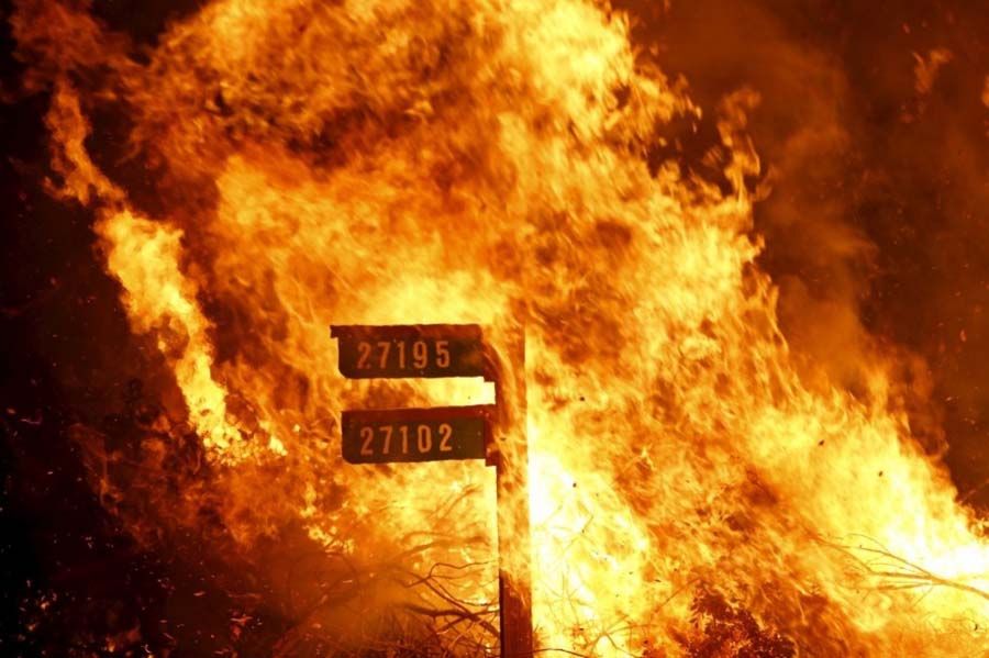 Flames from the Jerusalem Fire consume a sign containing addresses to homes along Morgan Valley Road in Lake County, California on August 12th, 2015. — Photograph: Robert Galbraith/Reuters.