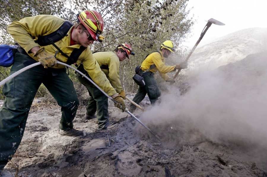 Novice firefighters Nathan Wilson, left, Ryan Christensen and Jesse Squibb, of Spokane Valley (Washington) Tech work to put out a hot spot remaining from a wildfire Friday, August 21st, 2015, in Tonasket, Washington. Out-of-control blazes in north-central Washington have destroyed buildings, but the situation is so chaotic that authorities have “no idea” how many homes may have been lost. — Photograph: Elaine Thompson/Associated Press.