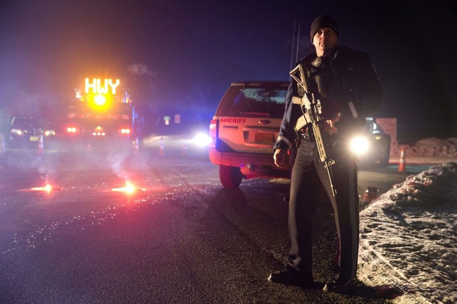 An Oregon State Police officer stands in front of a roadblock. — Photograph: Associated Press.