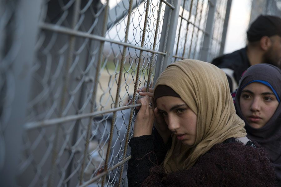 A young Syrian woman and other migrants at the metal fence separating Macedonia and Greece on February 28th. More than 5,500 refugees and migrants were reportedly stuck at the border.  Photograph: Petros Giannakouris/Associated Press.
