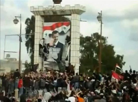This image taken from an amateur video shot in March 2011 shows protesters in Daraa defacing a giant poster of Syrian President Bashar al-Assad. — Photograph: Reuters.